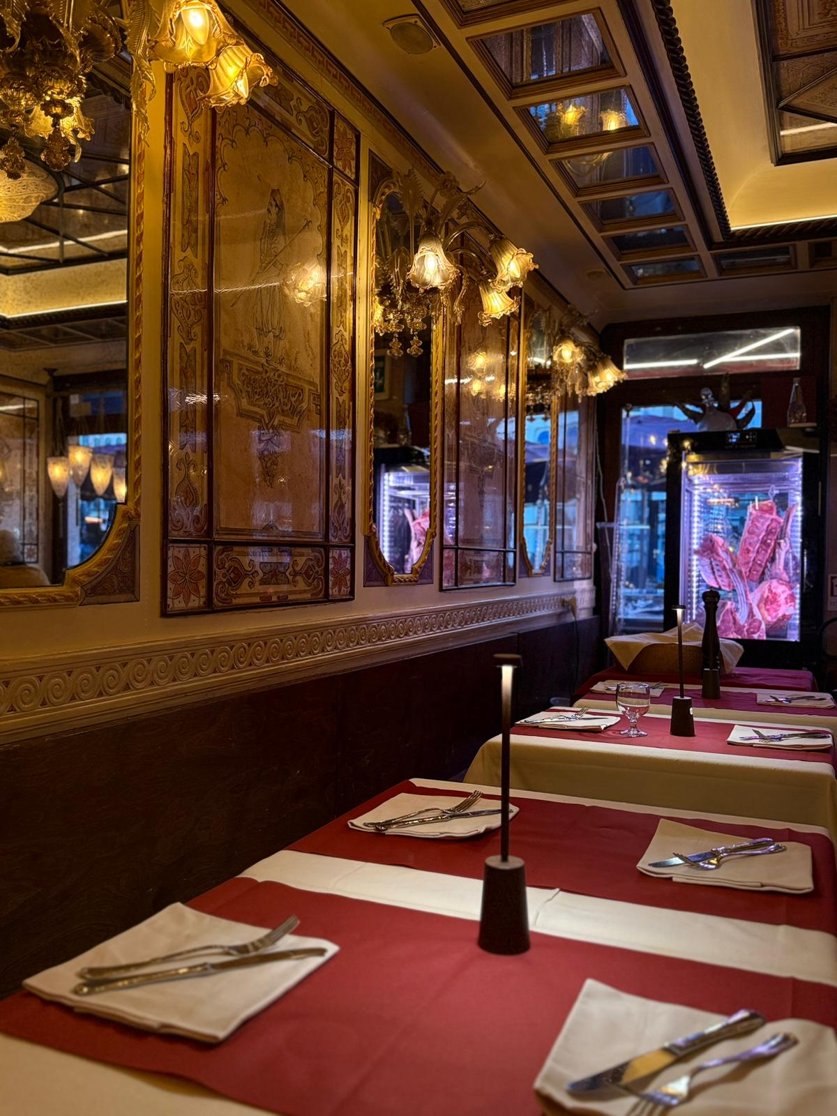 Sala interna con specchi dorati, lampadari di Murano e tavoli vestiti di rosso